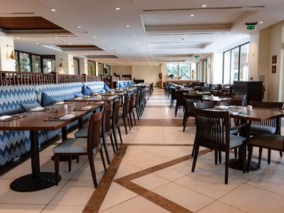 Hall moderna di un hotel con area salotto composta da sedie e tavoli accanto a un divano blu a motivi.