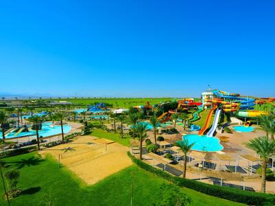 Área de parque acuático con toboganes, piscinas y áreas verdes bajo un cielo despejado.