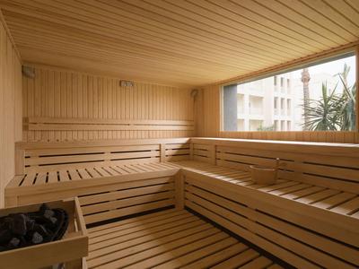 Sauna de madera clara con grandes ventanas y vistas a plantas en un hotel.