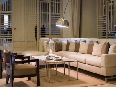 Modern eingerichtetes Wohnzimmer mit beige Sofa und Stühlen vor Fensterläden.