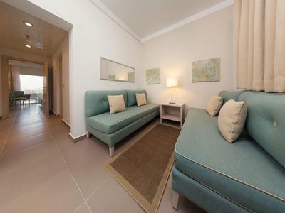 Sala luminosa con dos sofás azules, una alfombra y una mesa auxiliar con lámpara.