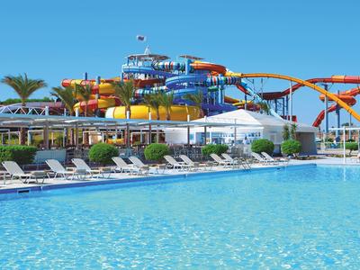 Grande piscina con lettini e scivoli d'acqua sullo sfondo in una giornata di sole