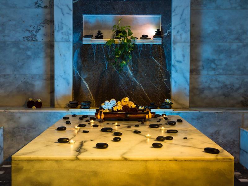Mesa de mármol con velas encendidas en un ambiente acogedor de spa o baño turco.