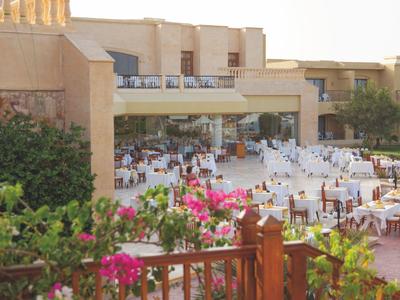 Hotel outdoor area with many set tables and blooming plants in the foreground