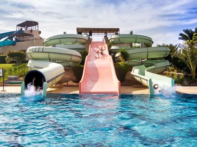 Colorful water slides lead into a large swimming pool under a sunny sky.