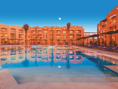 Hôtel avec grande piscine au coucher du soleil sous un ciel dégagé