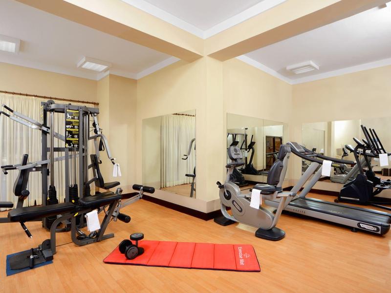 Brightly lit gym with workout machines and wall mirrors.