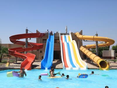 Kinder und Erwachsene spielen in einem Pool mit bunten Wasserrutschen bei strahlendem Sonnenschein.