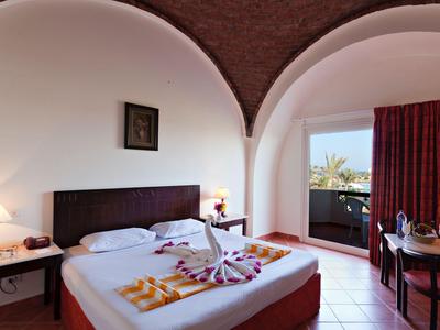 Habitación de hotel con cama doble, decorada con toallas y vista al balcón a la luz del día.