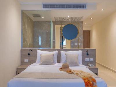 Modern hotel room with double bed, large mirrors, and warm lighting.