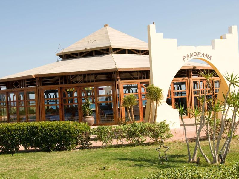 Wooden structure with glass panels near a white entrance labeled 'PASOFINA' on a grassy lawn.