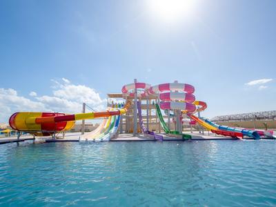 Parque acuático colorido con varias toboganes sobre una gran piscina con clima soleado.