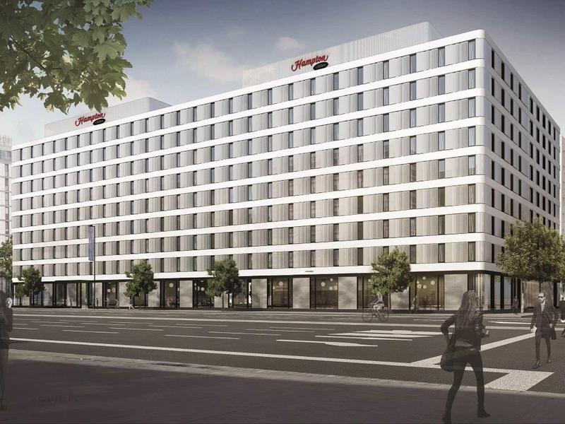 Großes, modernes Bürogebäude mit weißer Fassade und vielen Fenstern an einer Kreuzung.