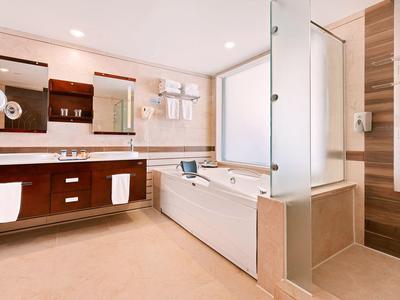 Helles Badezimmer mit Wanne, Duschkabine, Doppelwaschbecken und Holz-Fronten.