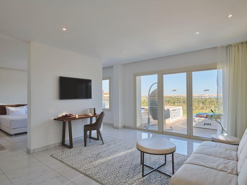 Helles Hotelzimmer mit Wohnzimmer, Terrasse und Blick auf die Landschaft.