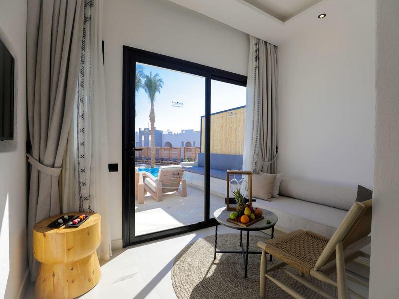 Helles Wohnzimmer mit Sofa, Holzstuhl, kleinem Tisch und Blick auf Terrasse mit Stühlen und Stadtblick.