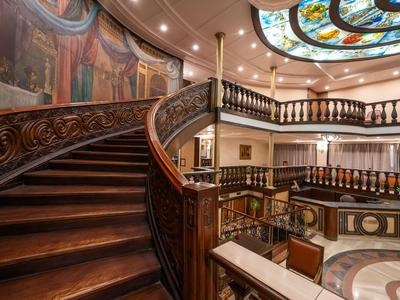 Elegante escalera de madera con barandilla ornamentada en un interior artísticamente diseñado.