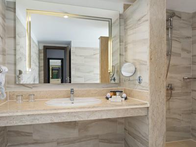 Helles Badezimmer mit großem Spiegel, Marmorwaschtisch und begehbarer Dusche in Naturtönen.