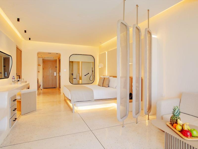 Helles modernes Hotelzimmer mit Doppelbett, weißen Wänden und minimalistischer Einrichtung.