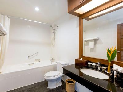 Modern bathroom with bathtub, toilet, and sink with a large mirror.