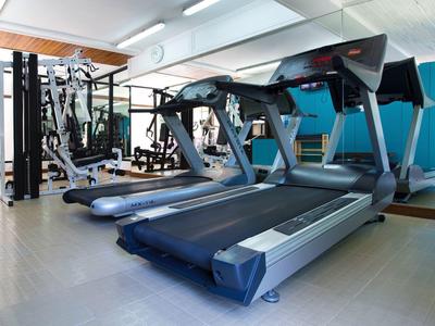 Moderner Fitnessraum mit zwei Laufbändern, Spiegelwand, Hanteln und blauem Akzent an der Wand.