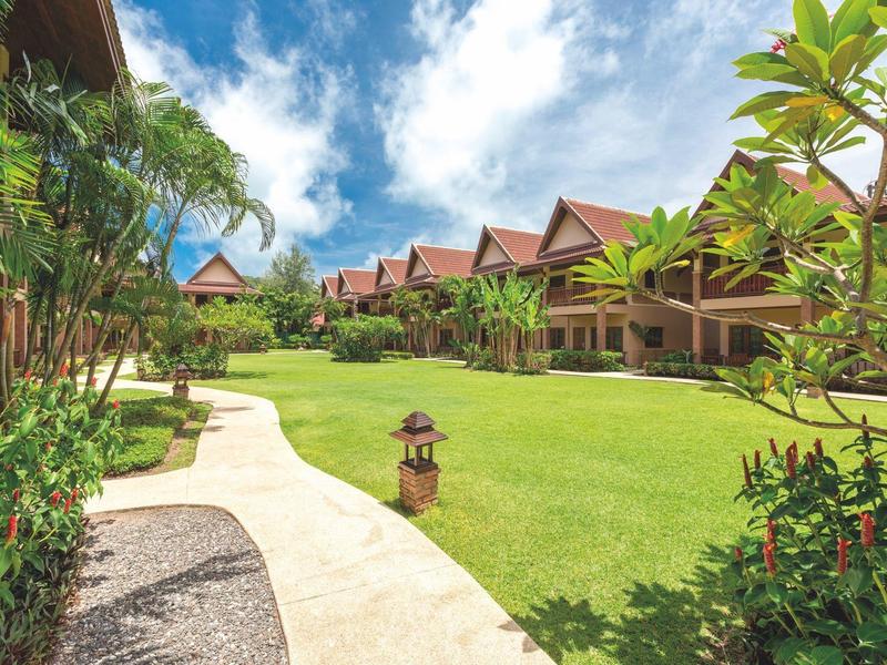 Green lawn with walkway surrounded by wooden houses and cloudy sky.