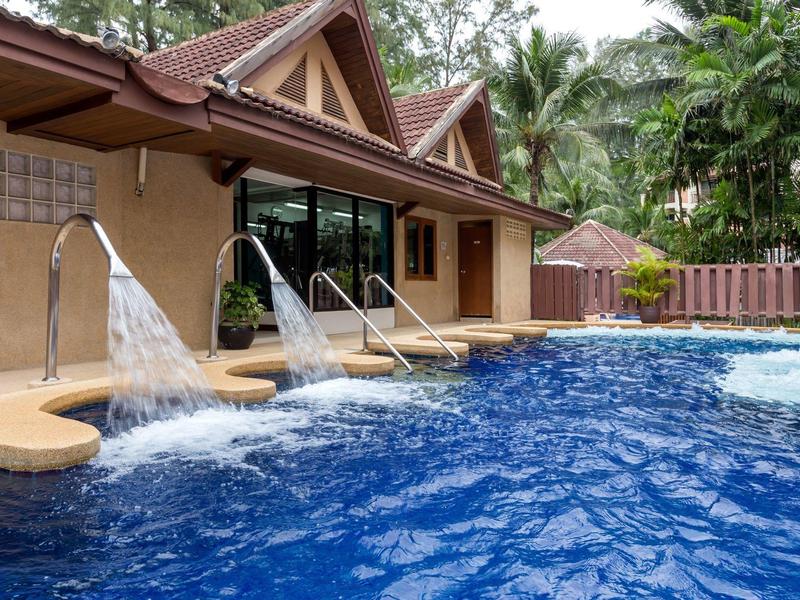 Outdoor pool with waterfalls beside a hotel building in a tropical setting