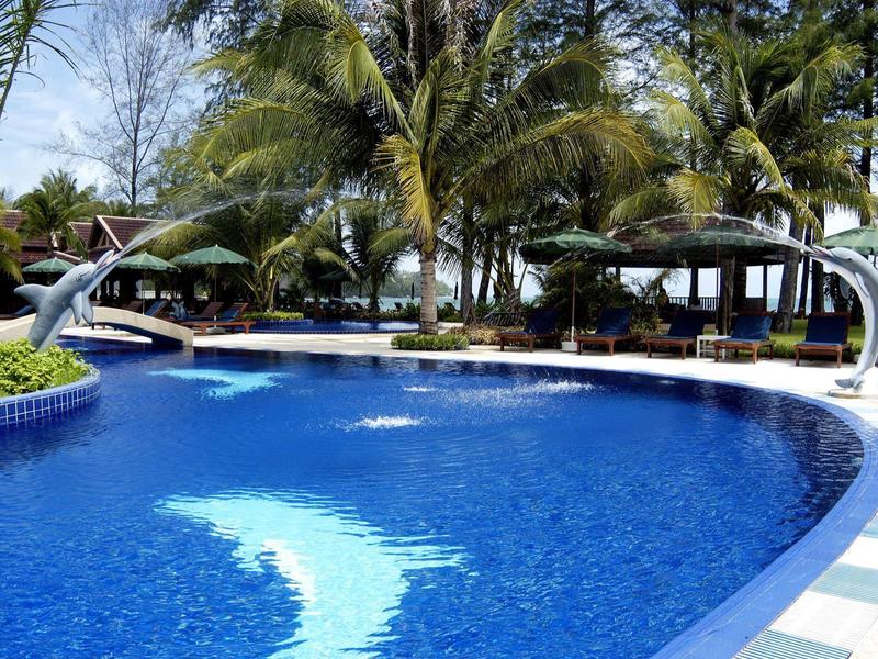Large curved pool with blue tiles and palm trees in the background.