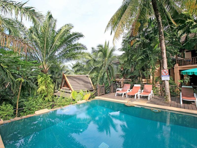 Einladender Pool mit blauer Wasserfläche, umgeben von Palmen und Liegestühlen in tropischer Natur.