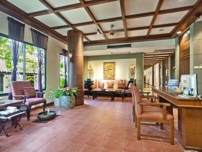 Heller, großzügiger Warteraum mit Holzmöbeln, großen Fenstern und terrakottafarbenem Boden.