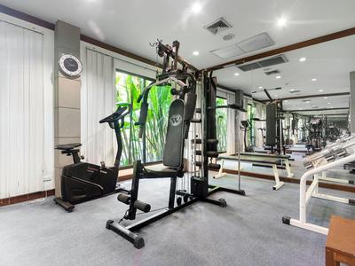 Moderner Fitnessraum mit Kraftgeräten, Spinning-Bike und Spiegelwand in hellem Raum.