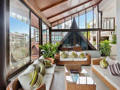 Helles Wohnzimmer mit hohen Fenstern, gemütlichen Sofas, Pflanzen und Blick auf eine Berglandschaft.