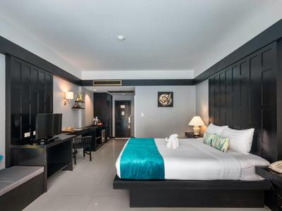 Modern eingerichtetes Hotelzimmer mit großem Bett, Schreibtisch und Fernseher.