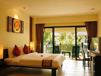 Hell eingerichtetes Hotelzimmer mit Doppelbett, Fernseher und Balkon mit Gartenblick.