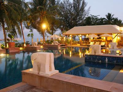 Abendliche Poolanlage mit beleuchtetem Pavillon und tropischer Umgebung im Hotel