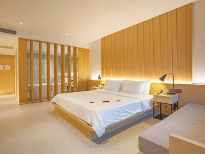 Modern eingerichtetes Hotelzimmer mit großem Doppelbett und Holzpaneelen an der Wand.