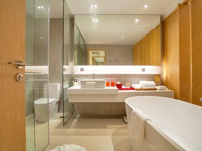 Modernes Badezimmer mit Badewanne, Doppelwaschbecken und Glasdusche in warmen Farbtönen.