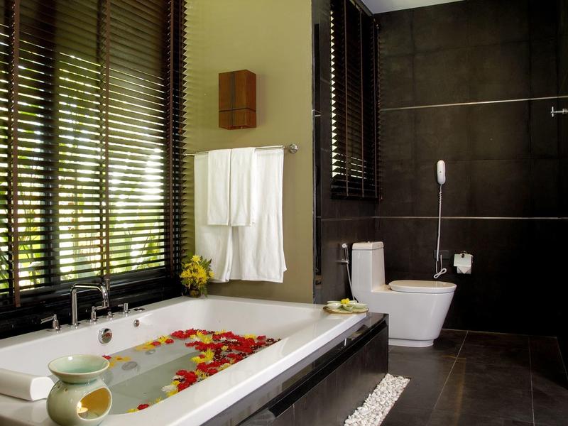 Modernes Badezimmer mit Badewanne, weißen Handtüchern und dunklen Fliesen.