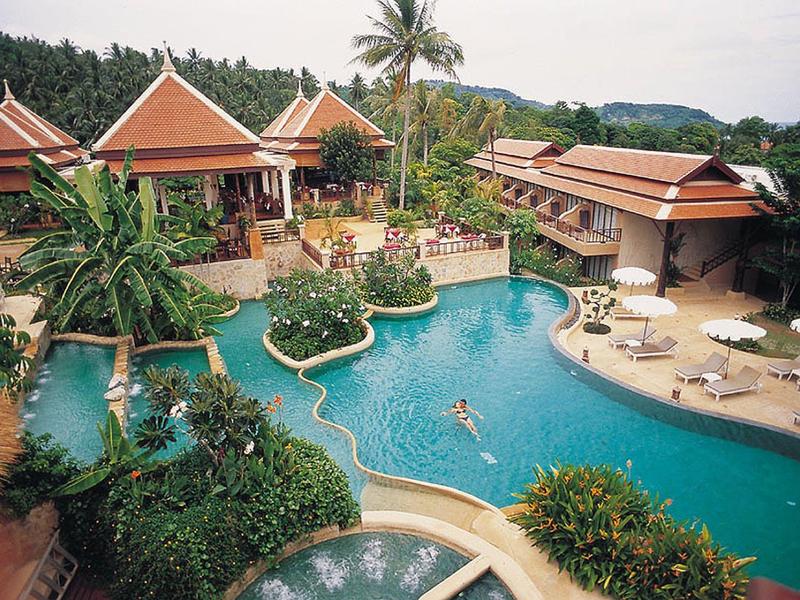 Luxueus hotelcomplex met grote zwembaden, omgeven door tropische planten en houten bungalows.