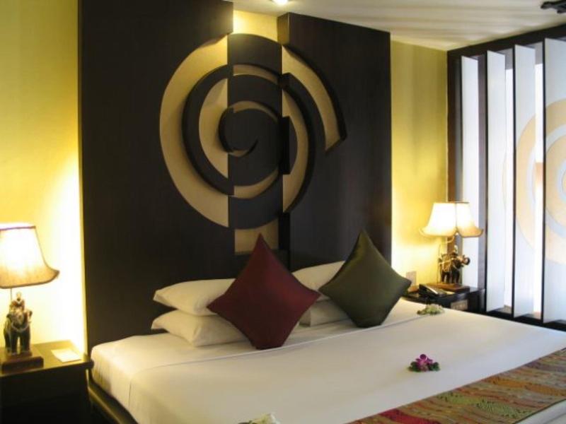 Modern ingerichte hotelkamer met wit bed, twee kussens en decoratieve wandverlichting.