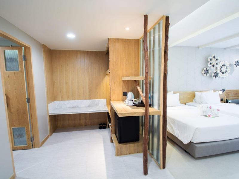 Modern hotelkamer met tweepersoonsbed, bureau en houten scheidingswand.