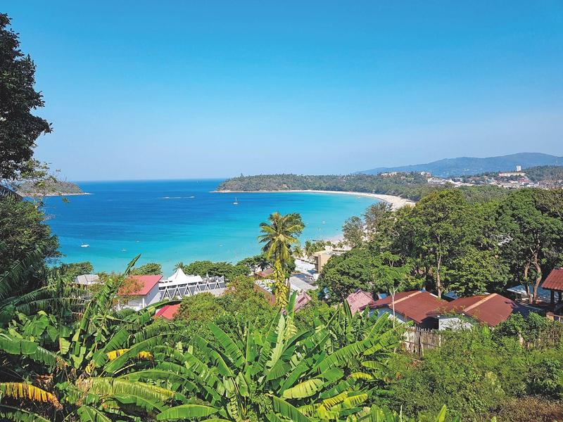 Uitzicht op een tropische kust met helder blauw water, strand en weelderige vegetatie.