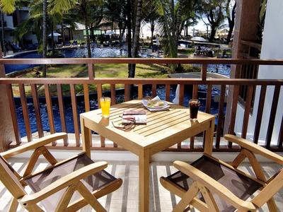 Balkon mit Holztisch, drei Stühlen, Zeitschriften und frisch gepresstem Orangensaft.
