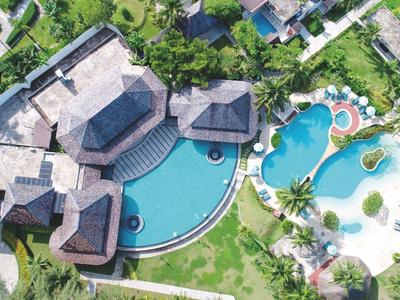 Luftaufnahme eines Resorts mit mehreren Pools, viel Grünfläche und umliegenden Gebäuden.