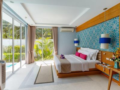 Helles Schlafzimmer mit großem Bett, buntem Kopfteil, Glaswand und Holzdetails.