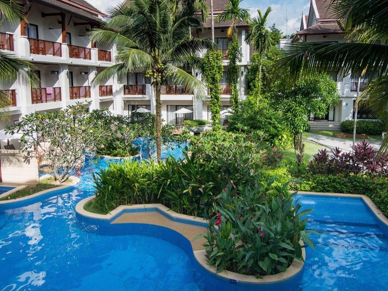 Ein tropischer Pool mit blauen Wasserflächen, umgeben von grünen Palmen und einem mehrstöckigen Hotel.