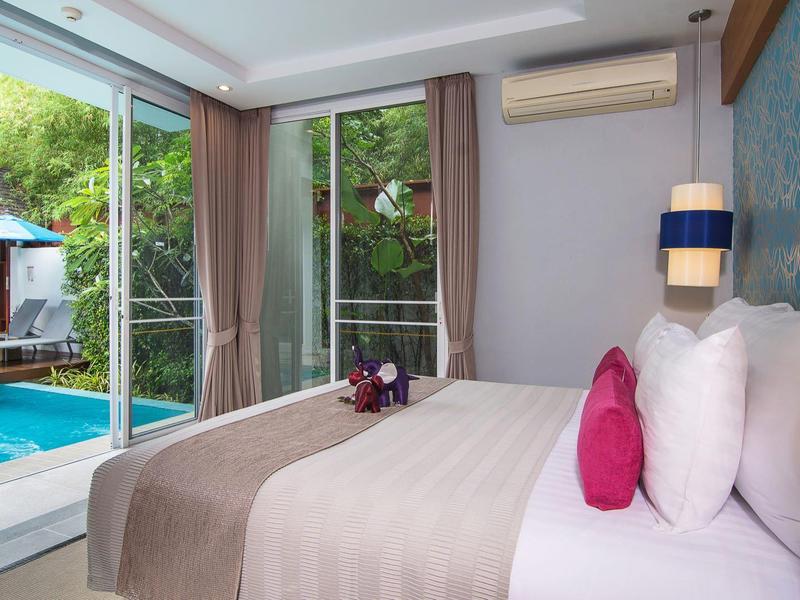 Modernes Schlafzimmer mit großem Bett, hellen Kissen und Blick auf Außenpool und Garten durch GlasschiebeTür.