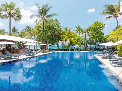 Großer blauer Pool mit Liegen und Sonnenschirmen, umgeben von Palmen bei sonnigem Wetter.