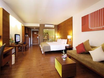 Modern eingerichtetes Hotelzimmer mit Doppelbett, Sofa und Fernseher auf Holzfußboden.