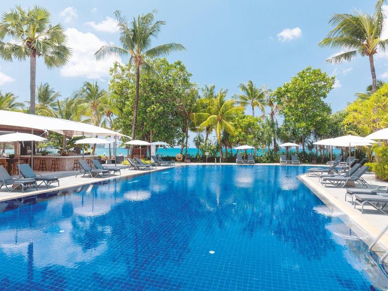 Großer Pool mit Liegestühlen und Sonnenschirmen in tropischer Hotelanlage